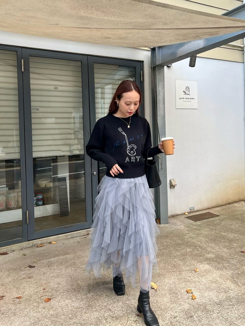 ブラック系のニット/セーター、ブラック系のバッグ、ブラック系のブーツを着用したレディースの秋コーディネートの3枚目の写真