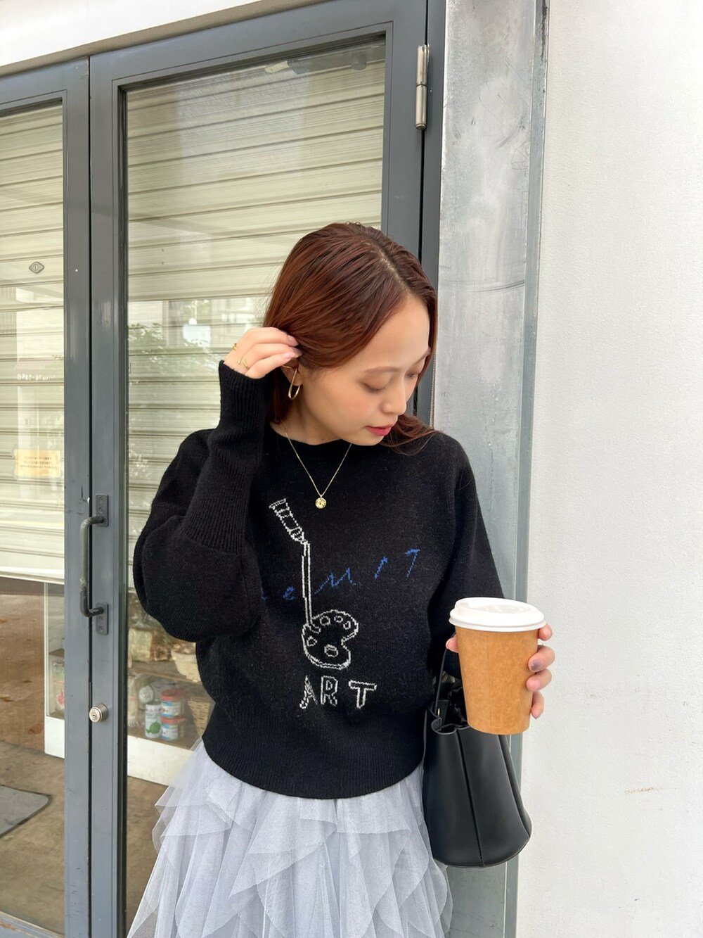 ブラック系のニット/セーター、ブラック系のバッグ、ブラック系のブーツを着用したレディースの秋コーディネートの2枚目の写真