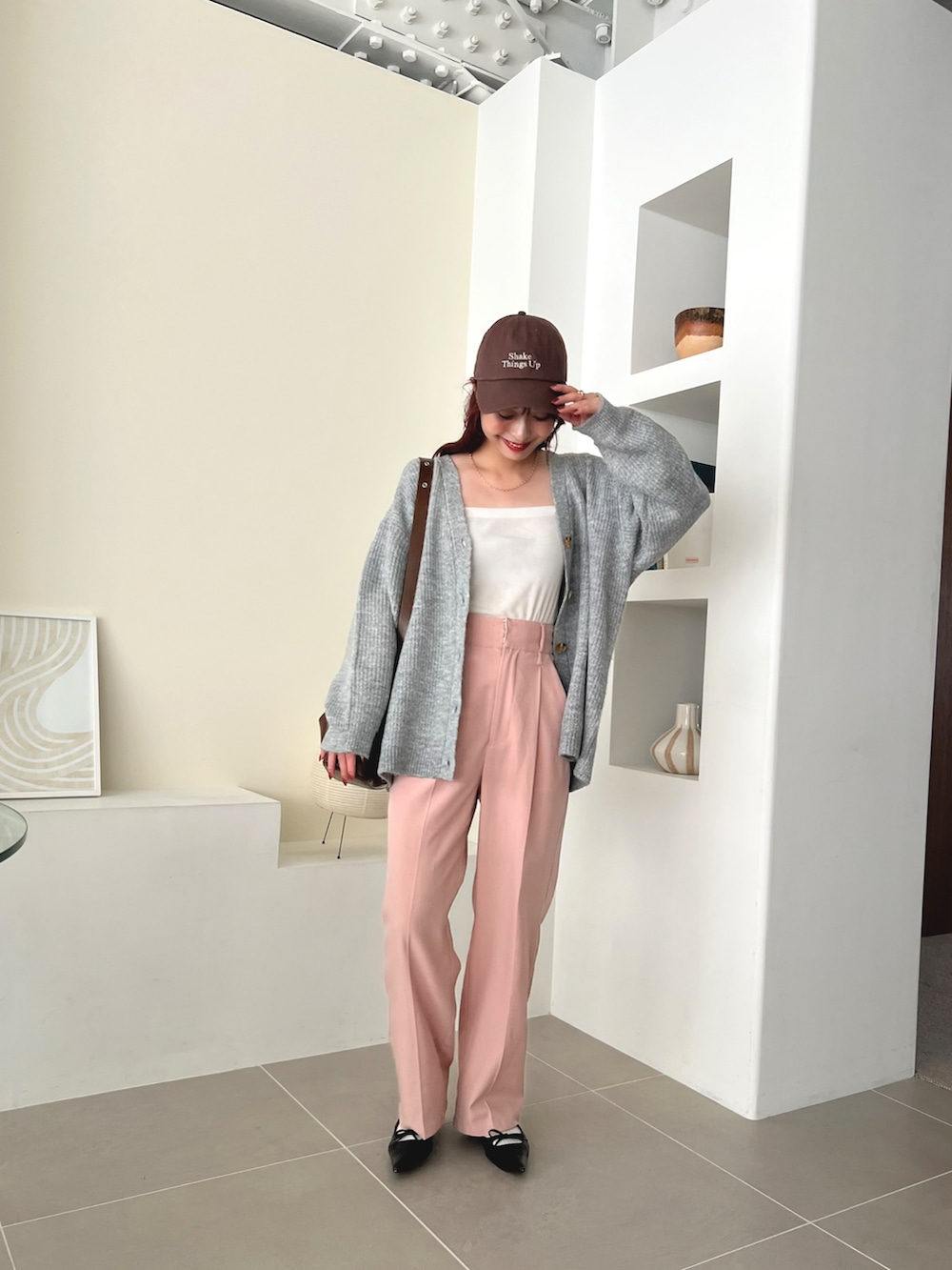 ブラウン系のバッグ、ピンク系のスラックス、ブラック系のパンプスを着用したレディースの秋コーディネートの2枚目の写真