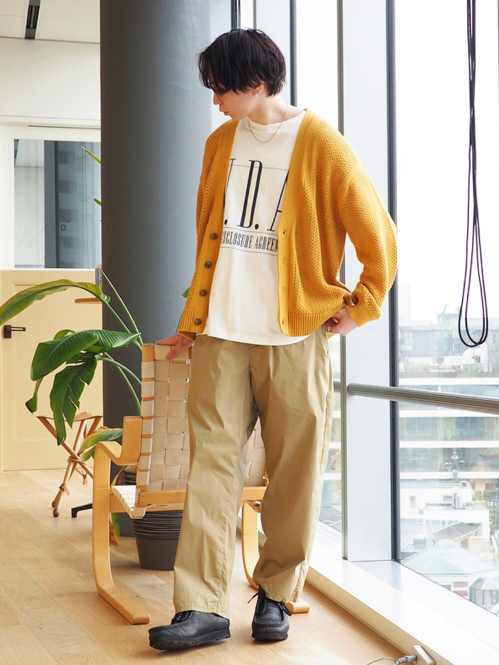 イエロー系のニット/セーター、ホワイト系のTシャツ/カットソー、ブラック系のブーツを着用したメンズの冬コーディネートの2枚目の写真