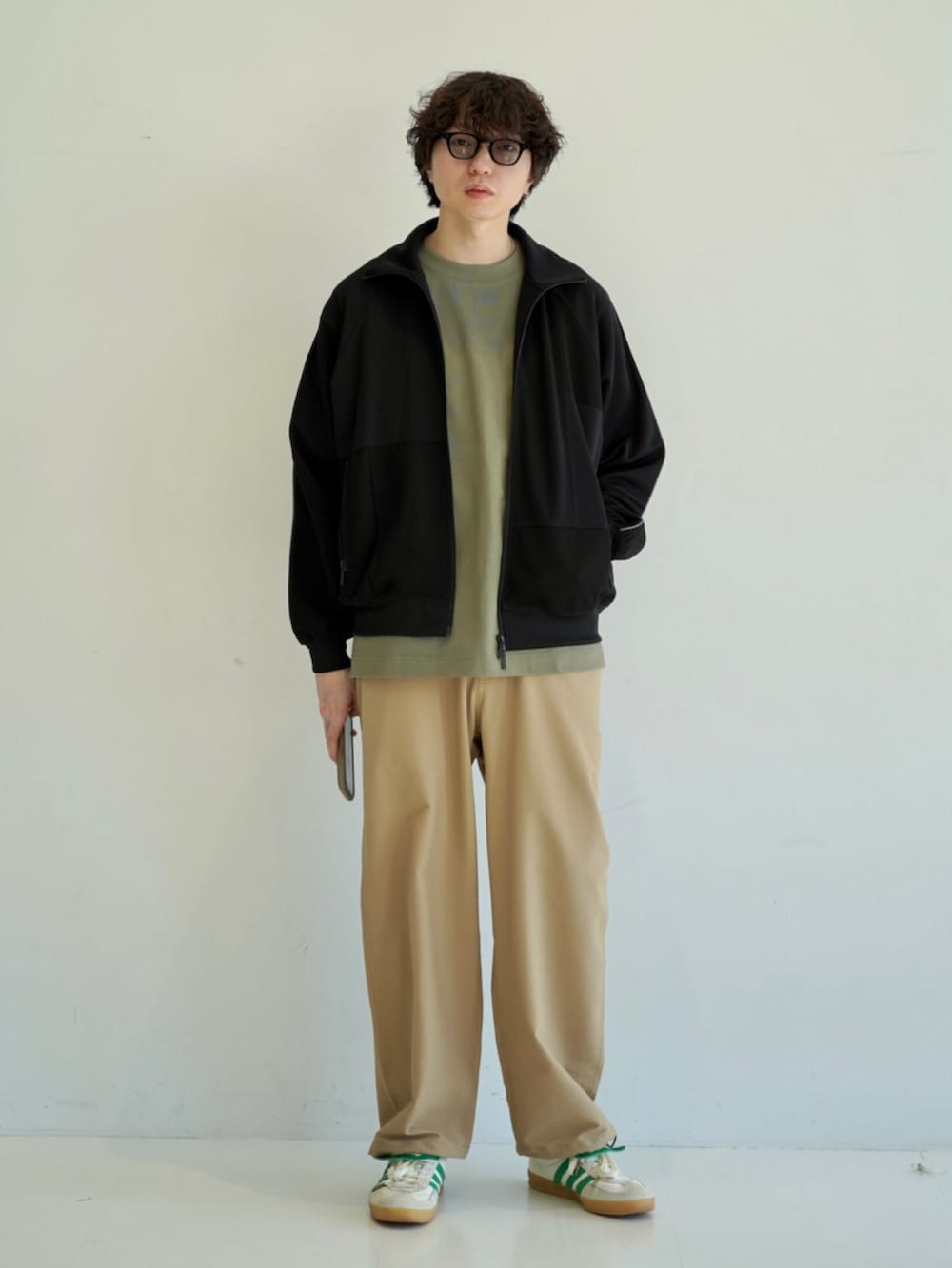 グリーン系のTシャツ/カットソー、ホワイト系のスニーカー、ブラック系のジャージを着用したメンズの冬コーディネートの3枚目の写真