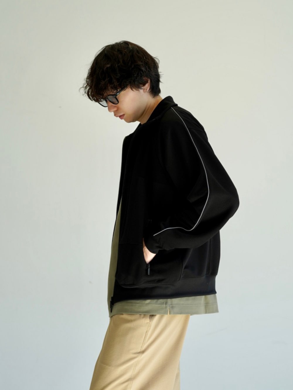 グリーン系のTシャツ/カットソー、ホワイト系のスニーカー、ブラック系のジャージを着用したメンズの冬コーディネートの4枚目の写真