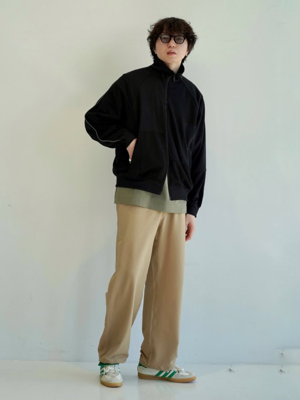 グリーン系のTシャツ/カットソー、ホワイト系のスニーカー、ブラック系のジャージを着用したメンズの冬コーディネートの2枚目の写真