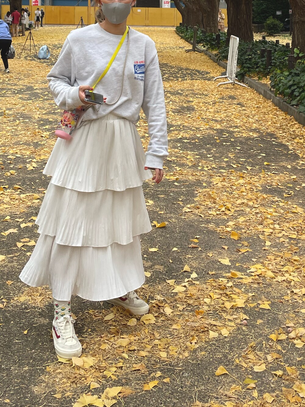 グレー系のスウェット、ホワイト系のスカート、レッド系のスニーカーを着用したレディースの秋コーディネートの2枚目の写真