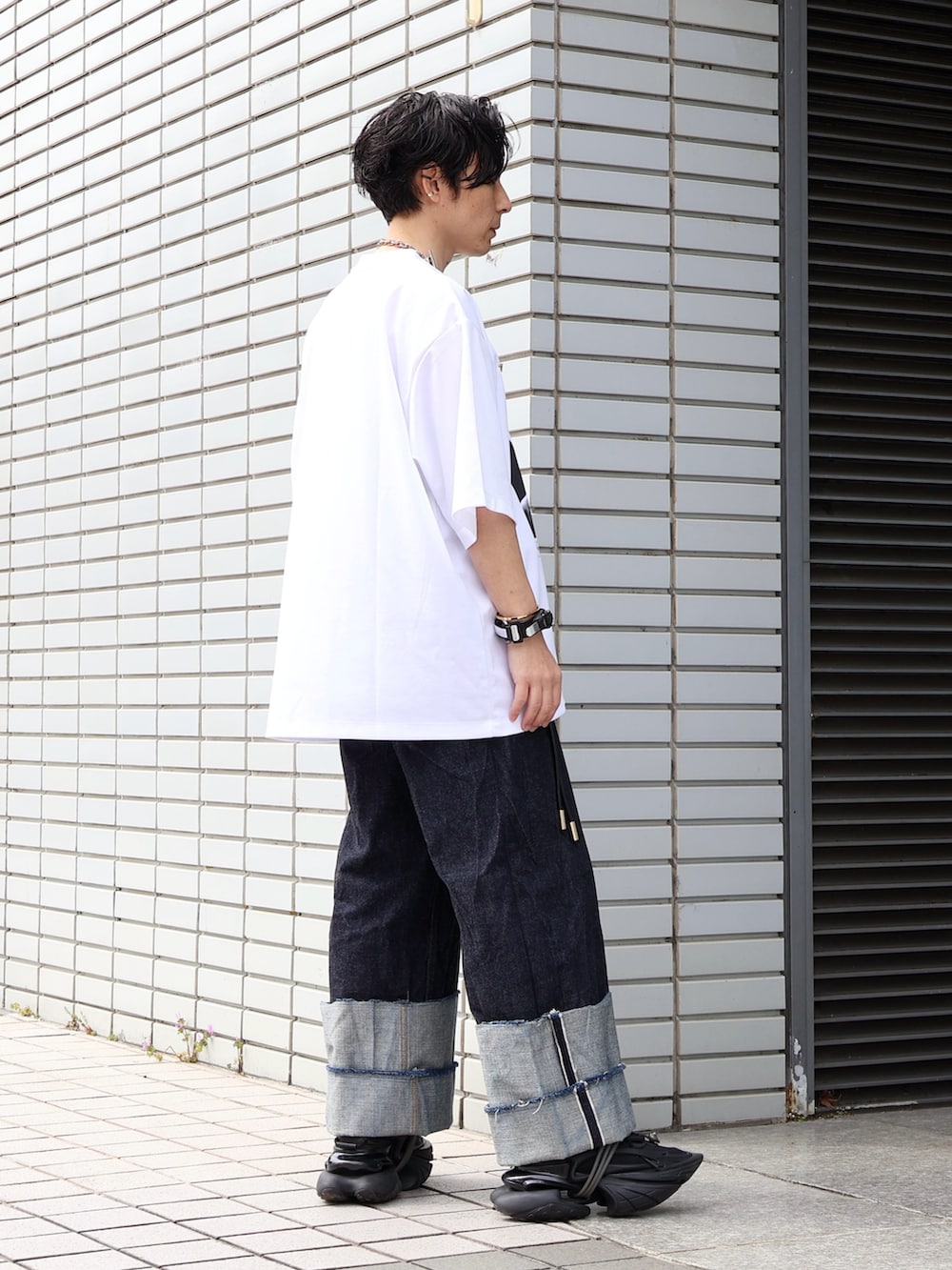 ブラック系のスニーカー、ブルー系のデニムパンツ、ブラック系のボストンバッグを着用したメンズの秋コーディネートの3枚目の写真