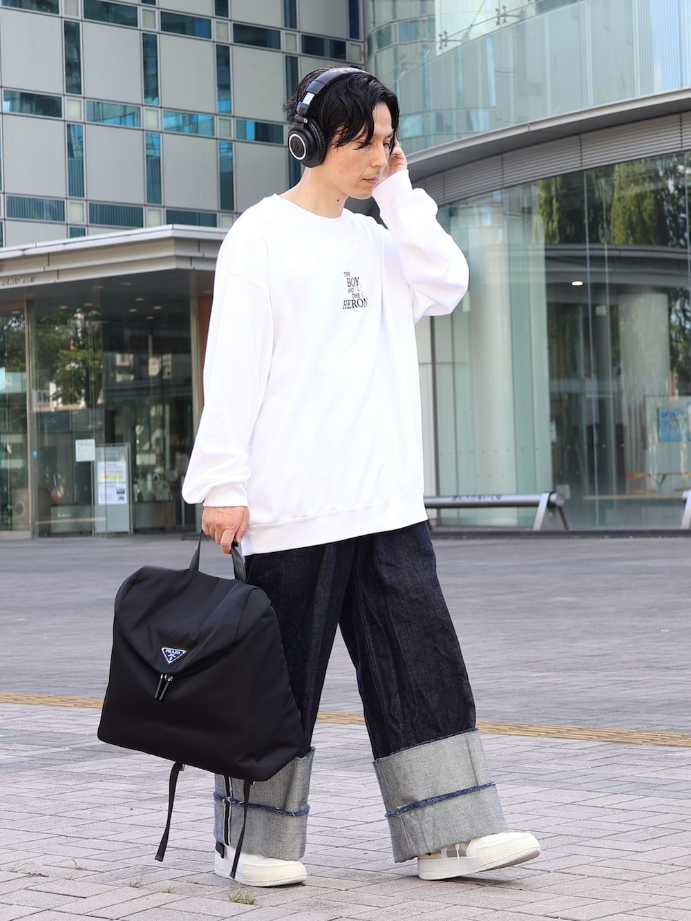 ブルー系のデニムパンツ、ブラック系のバックパック/リュック、ホワイト系のスニーカーを着用したメンズの冬コーディネートの2枚目の写真