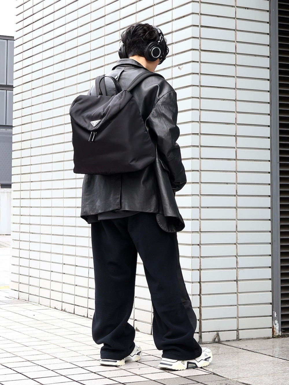 ブラック系のテーラードジャケット、ホワイト系のスニーカー、ブラック系のバックパック/リュックを着用したメンズの冬コーディネートの3枚目の写真