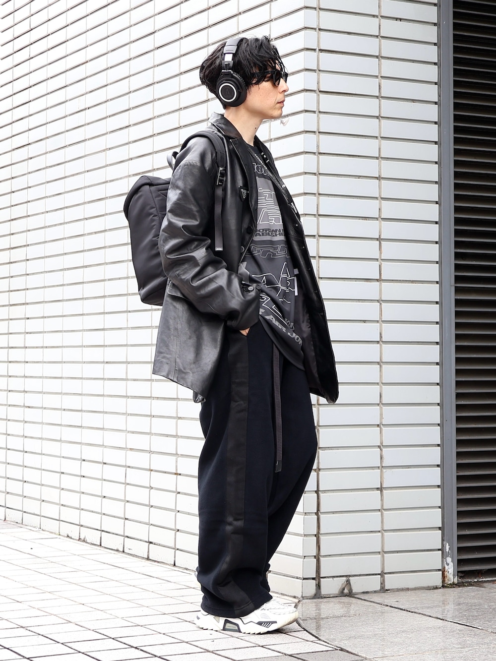 ブラック系のテーラードジャケット、ホワイト系のスニーカー、ブラック系のバックパック/リュックを着用したメンズの冬コーディネートの2枚目の写真