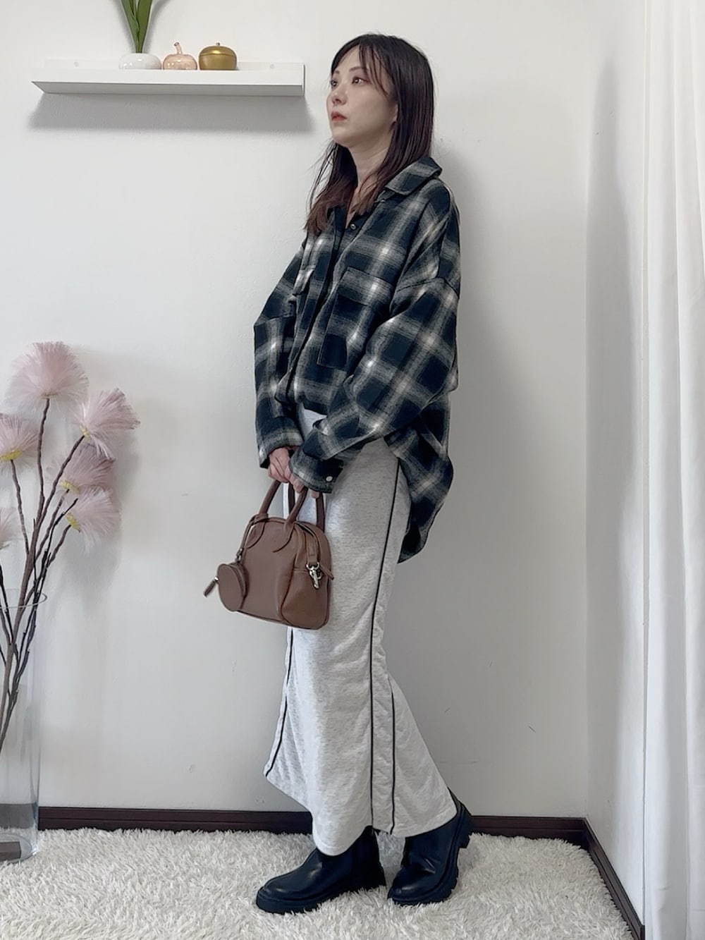 ブラック系のシャツ/ブラウス、ブラック系のブーツ、ベージュ系のスカートを着用したレディースの秋コーディネートの2枚目の写真