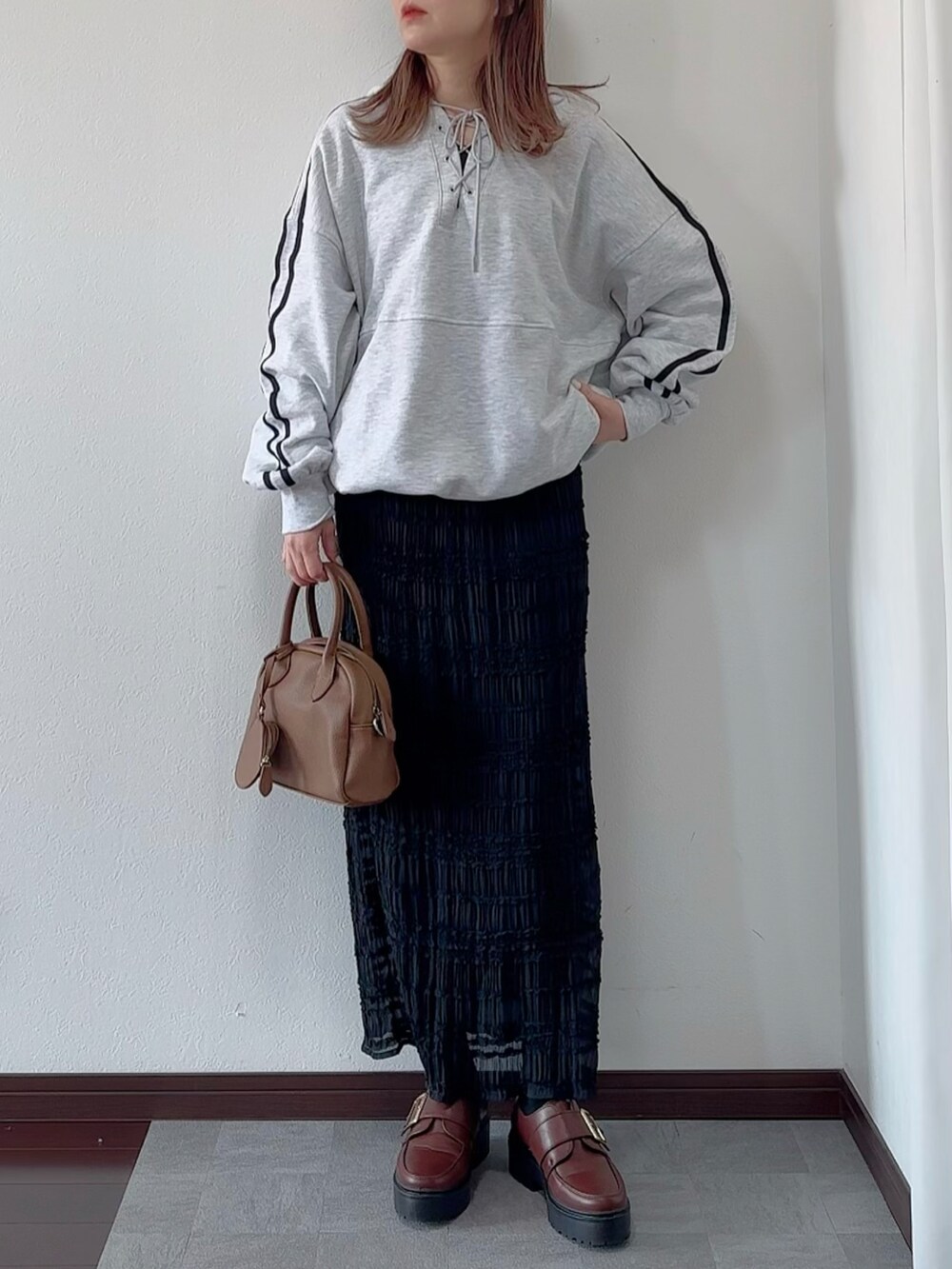 グレー系のパーカー、ブラック系のスカート、ブラウン系のローファーを着用したレディースの冬コーディネートの2枚目の写真