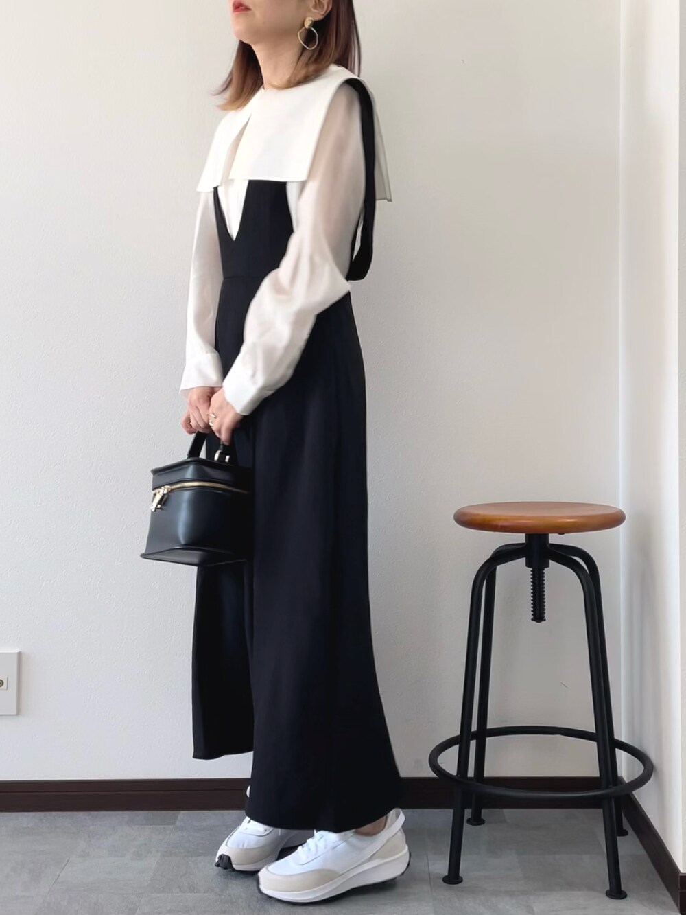 ブラック系のジャンパースカート、ホワイト系のシャツ/ブラウス、ブラック系のショルダーバッグを着用したレディースの春コーディネートの2枚目の写真