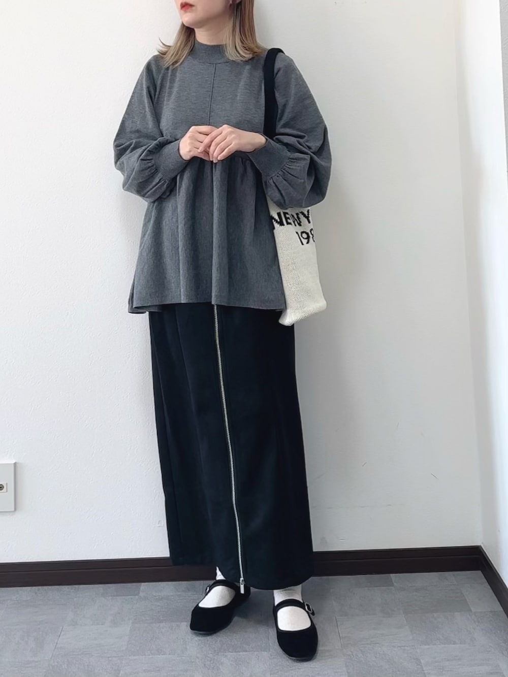 グレー系のニット/セーター、ベージュ系のバッグ、ブラック系のスカートを着用したレディースの冬コーディネートの2枚目の写真