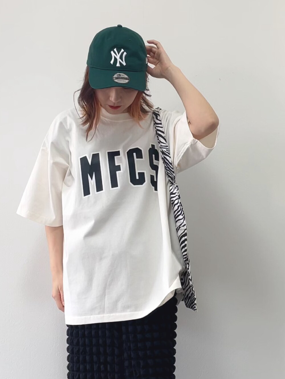 ホワイト系のTシャツ/カットソー、ブラック系のスカート、ホワイト系のスニーカーを着用したレディースの春コーディネートの2枚目の写真