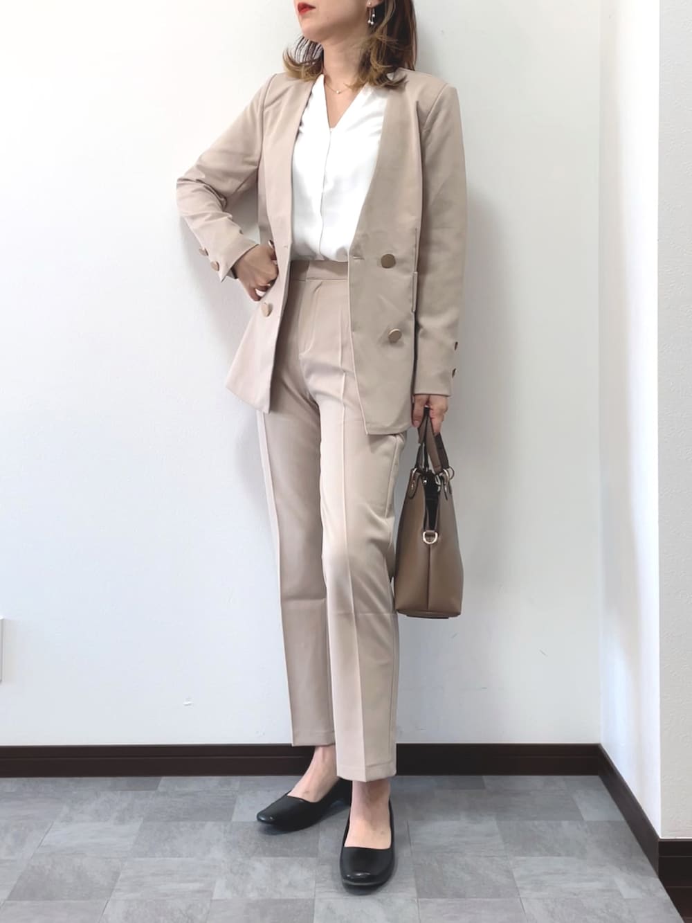 ベージュ系のセットアップ、ベージュ系のボストンバッグ、その他のピアス（両耳用）を着用したレディースの冬コーディネートの2枚目の写真