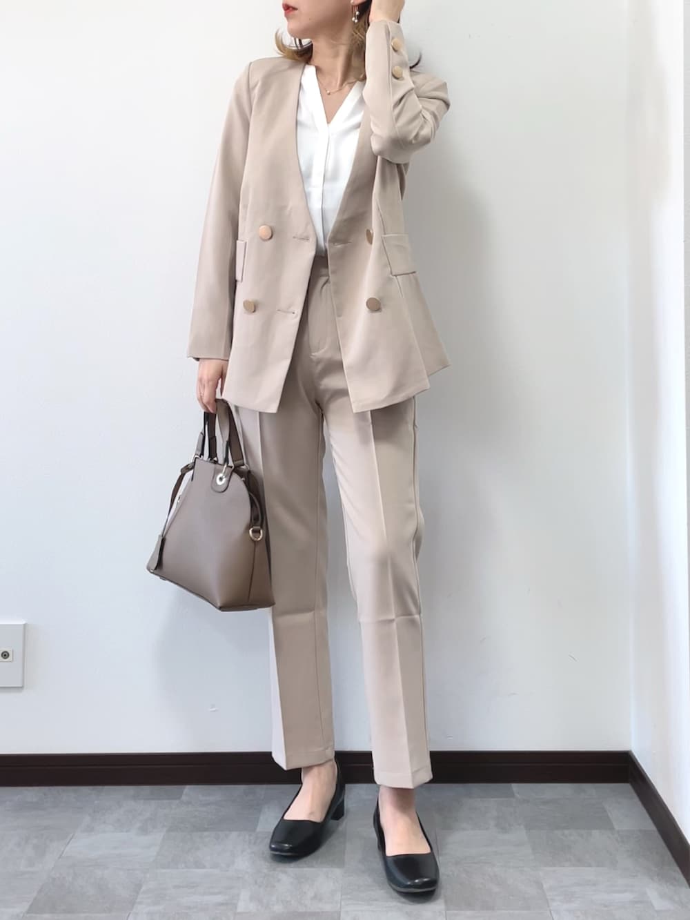 ベージュ系のセットアップ、ベージュ系のボストンバッグ、その他のピアス（両耳用）を着用したレディースの冬コーディネートの3枚目の写真