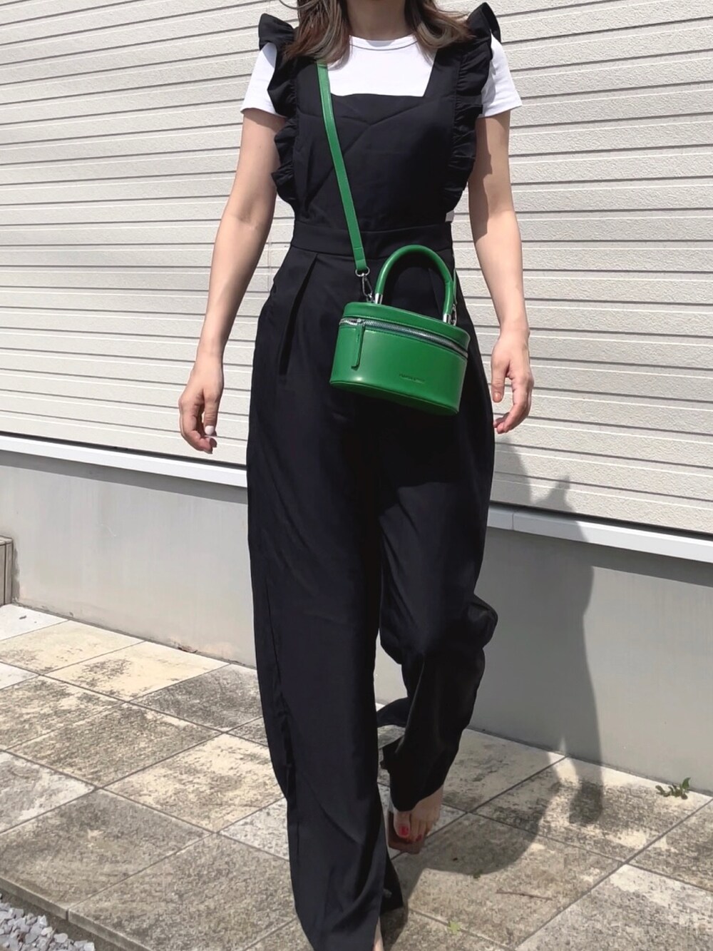 ブラック系のオールインワン・サロペット、グリーン系のハンドバッグ、ベージュ系のサンダルを着用したレディースの夏コーディネートの2枚目の写真