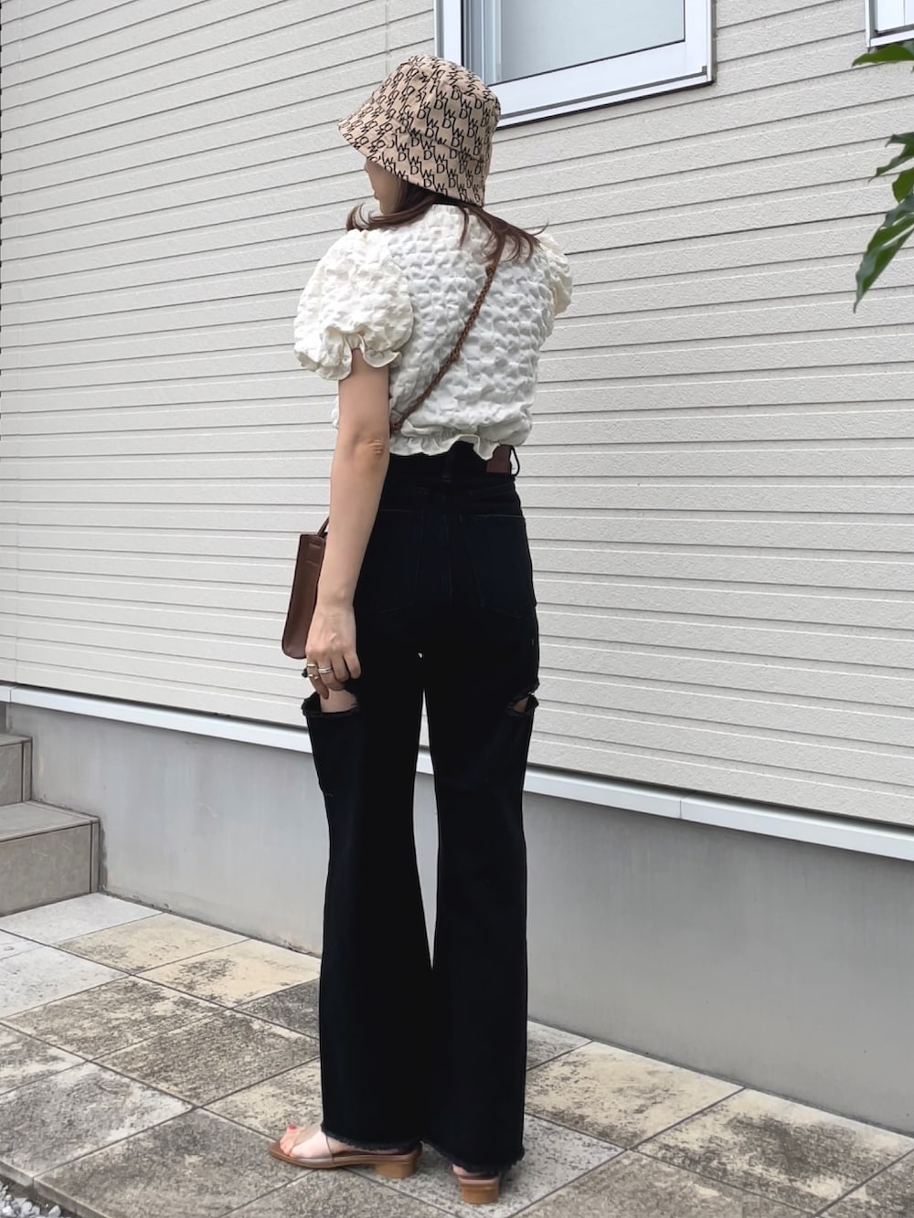 ブラック系のデニムパンツ、ベージュ系のサンダル、ホワイト系のシャツ/ブラウスを着用したレディースの夏コーディネートの2枚目の写真