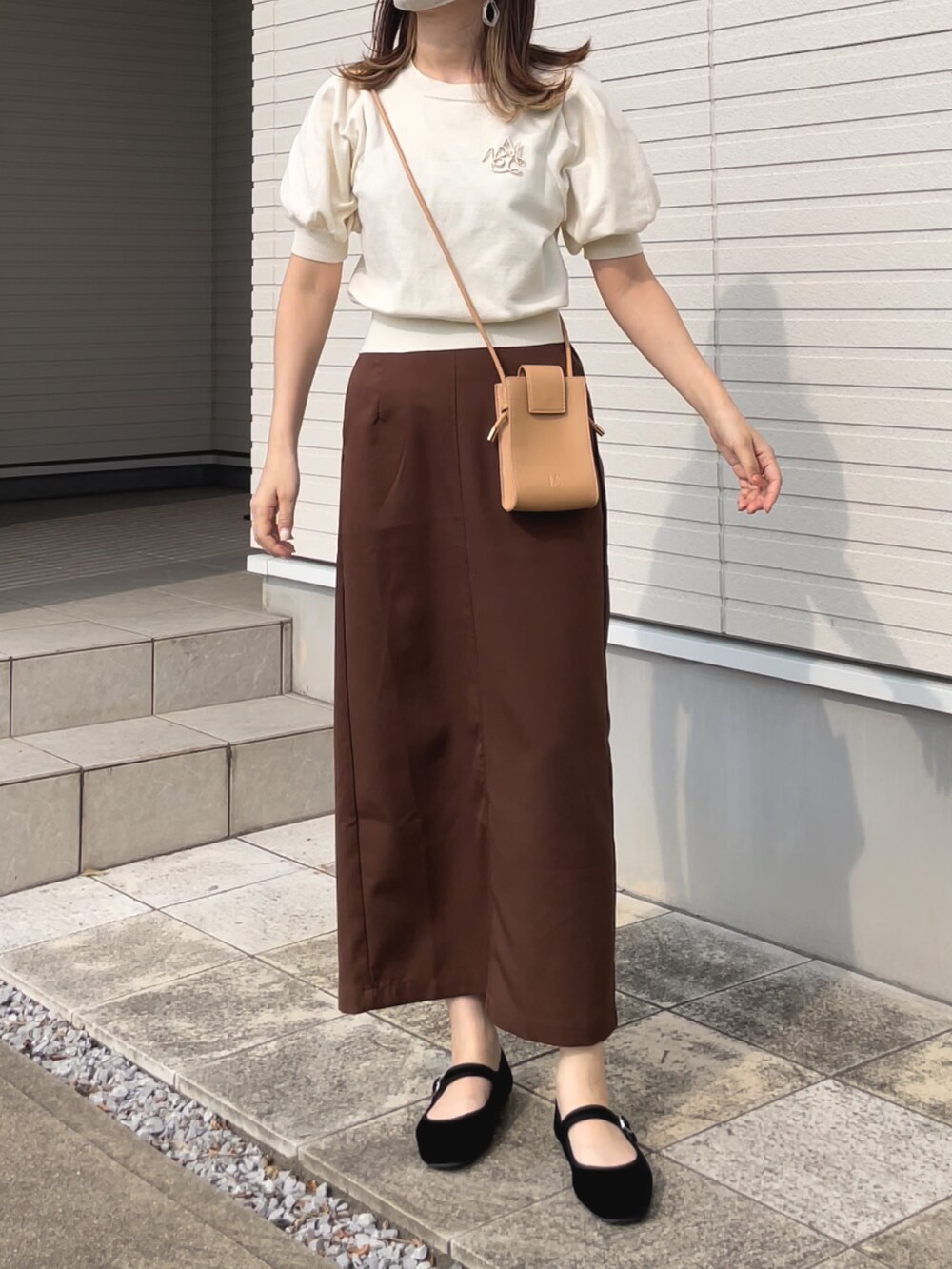 ホワイト系のニット/セーター、イエロー系のショルダーバッグ、ブラウン系のスカートを着用したレディースの夏コーディネートの2枚目の写真