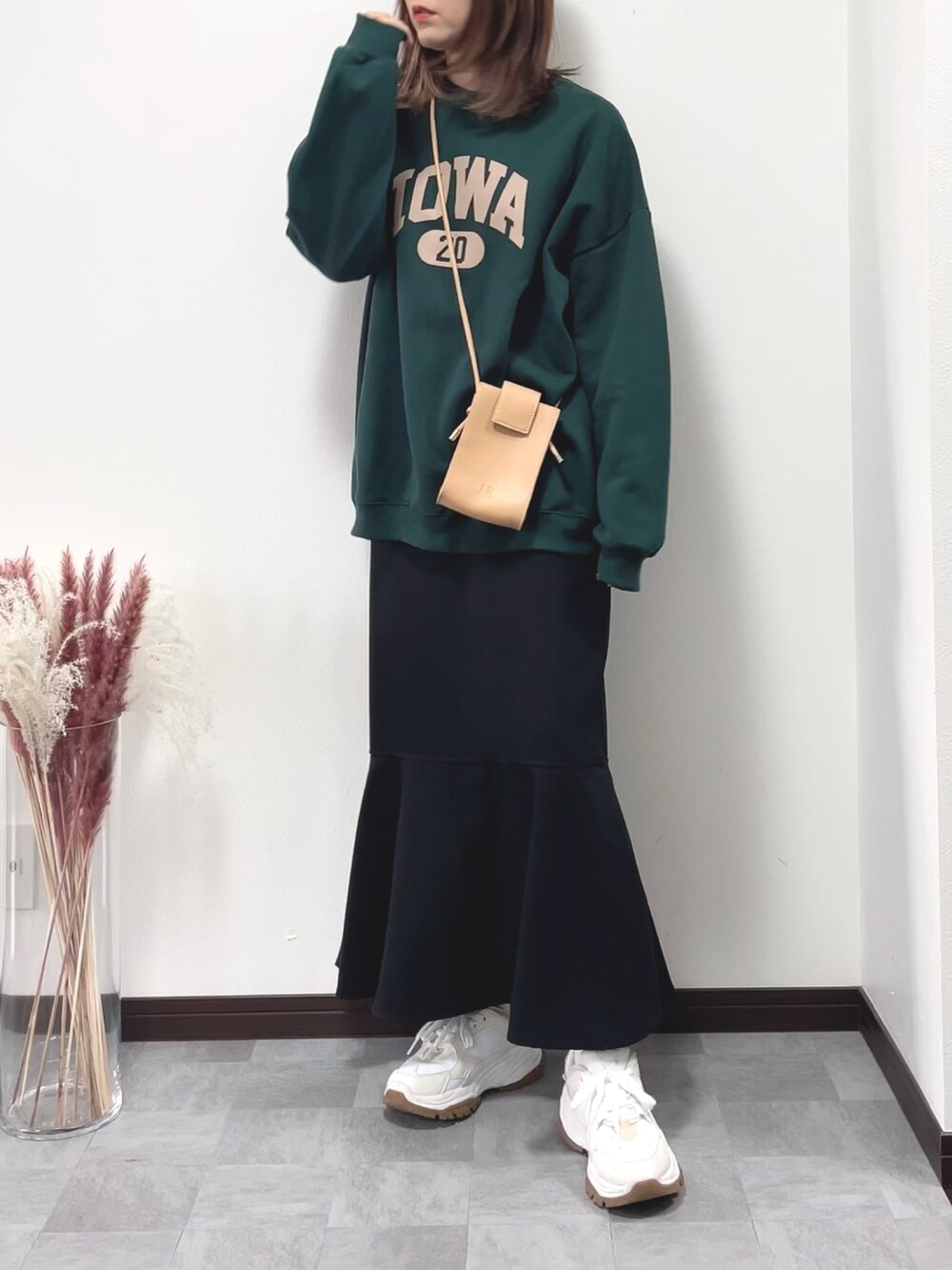 グリーン系のスウェット、イエロー系のショルダーバッグ、ブラック系のスカートを着用したレディースの秋コーディネートの2枚目の写真