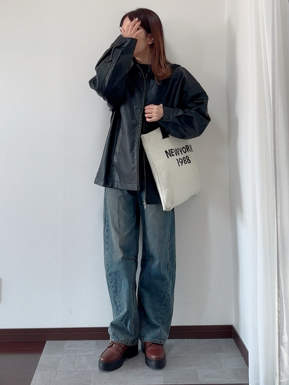 ブラック系のブルゾン、ブルー系のデニムパンツ、ベージュ系のバッグを着用したレディースの冬コーディネートの2枚目の写真