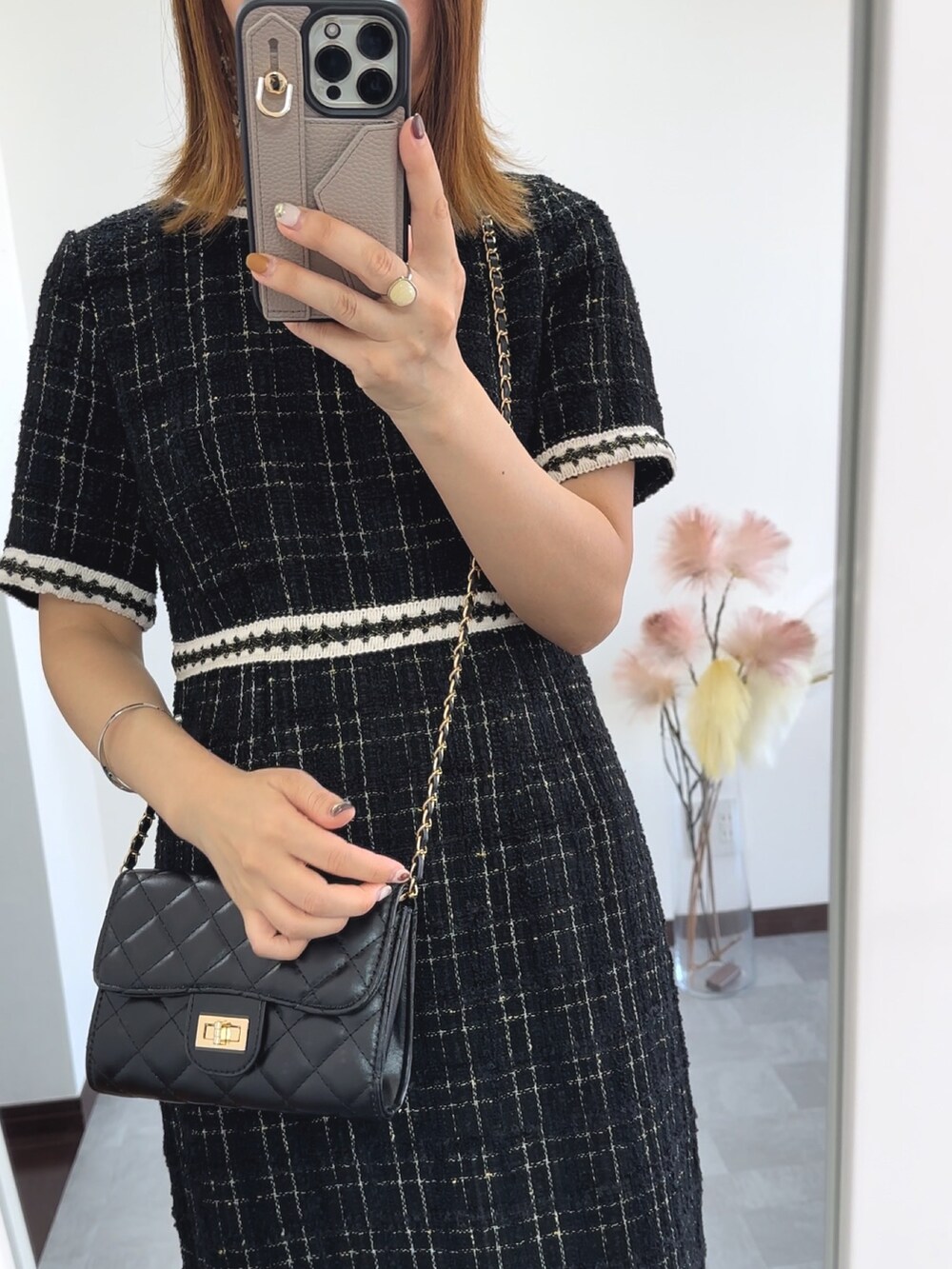 ブラック系のドレス、ブラック系のショルダーバッグ、ホワイト系のパンプスを着用したレディースの秋コーディネートの4枚目の写真