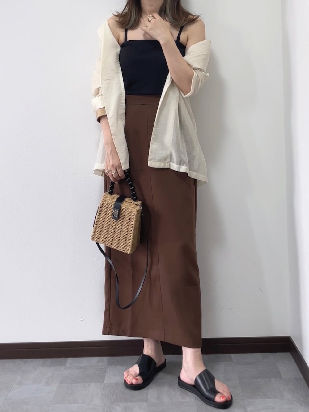 ホワイト系のテーラードジャケット、ブラウン系のスカート、ブラック系のサンダルを着用したレディースの夏コーディネートの2枚目の写真