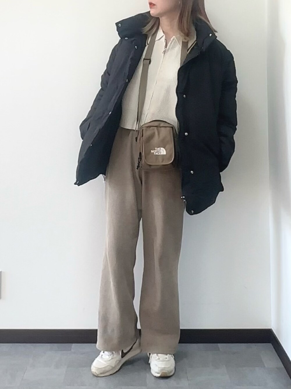 ブラック系のダウンジャケット/コート、ホワイト系のスニーカー、ホワイト系のニット/セーターを着用したレディースの冬コーディネートの2枚目の写真