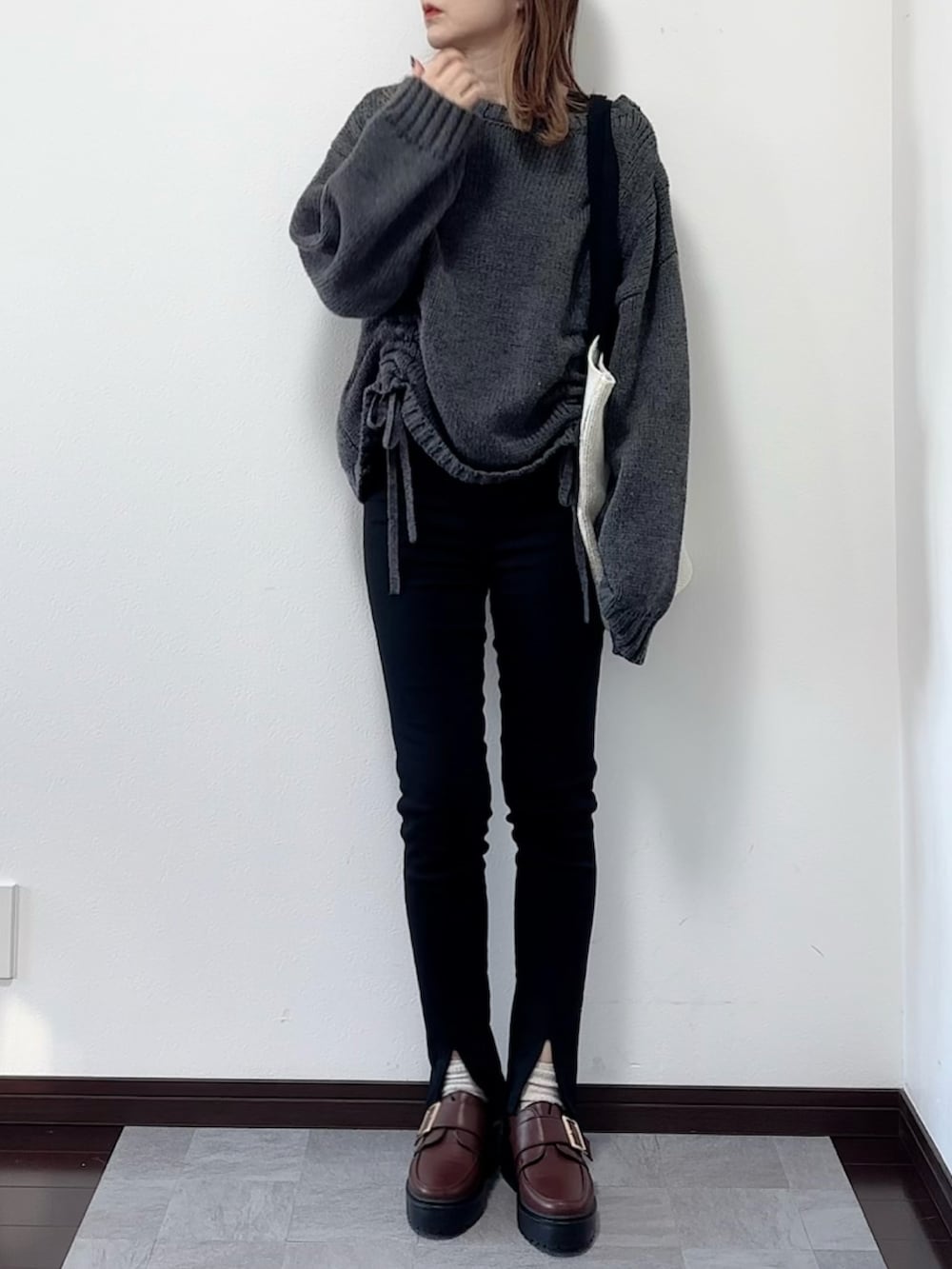 グレー系のニット/セーター、ブラック系のその他パンツ、ブラウン系のローファーを着用したレディースの秋コーディネートの2枚目の写真