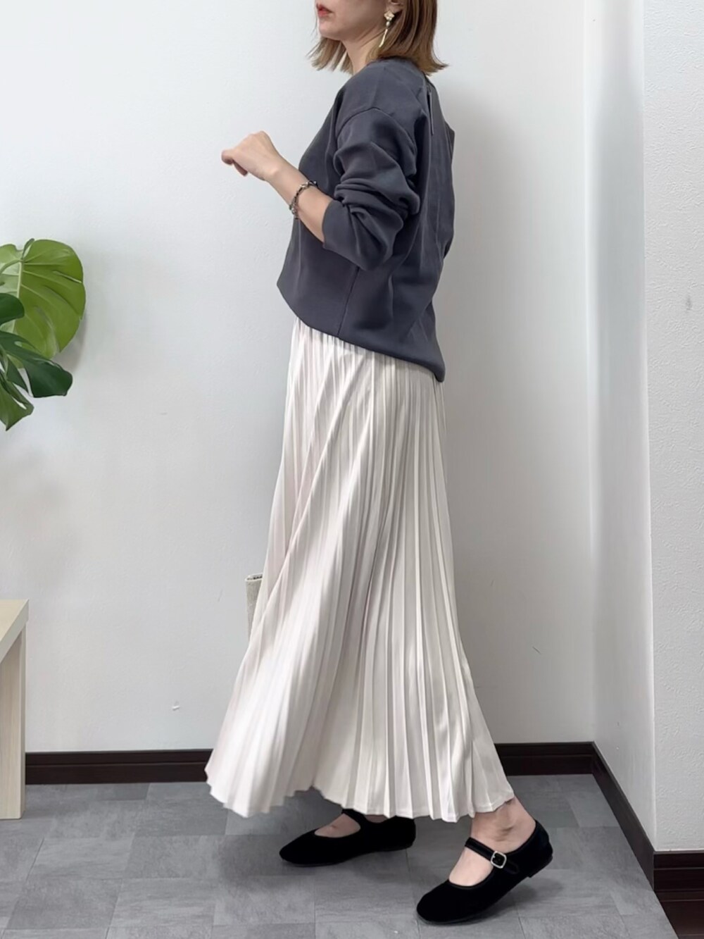 グレー系のニット/セーター、ホワイト系のスカート、ベージュ系のバッグを着用したレディースの秋コーディネートの2枚目の写真