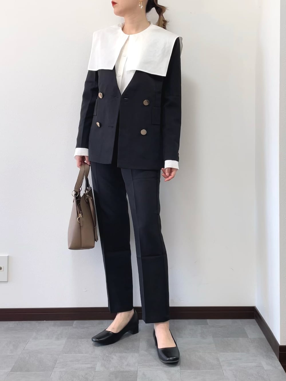 ブラック系のセットアップ、ベージュ系のボストンバッグ、ホワイト系のシャツ/ブラウスを着用したレディースの冬コーディネートの2枚目の写真