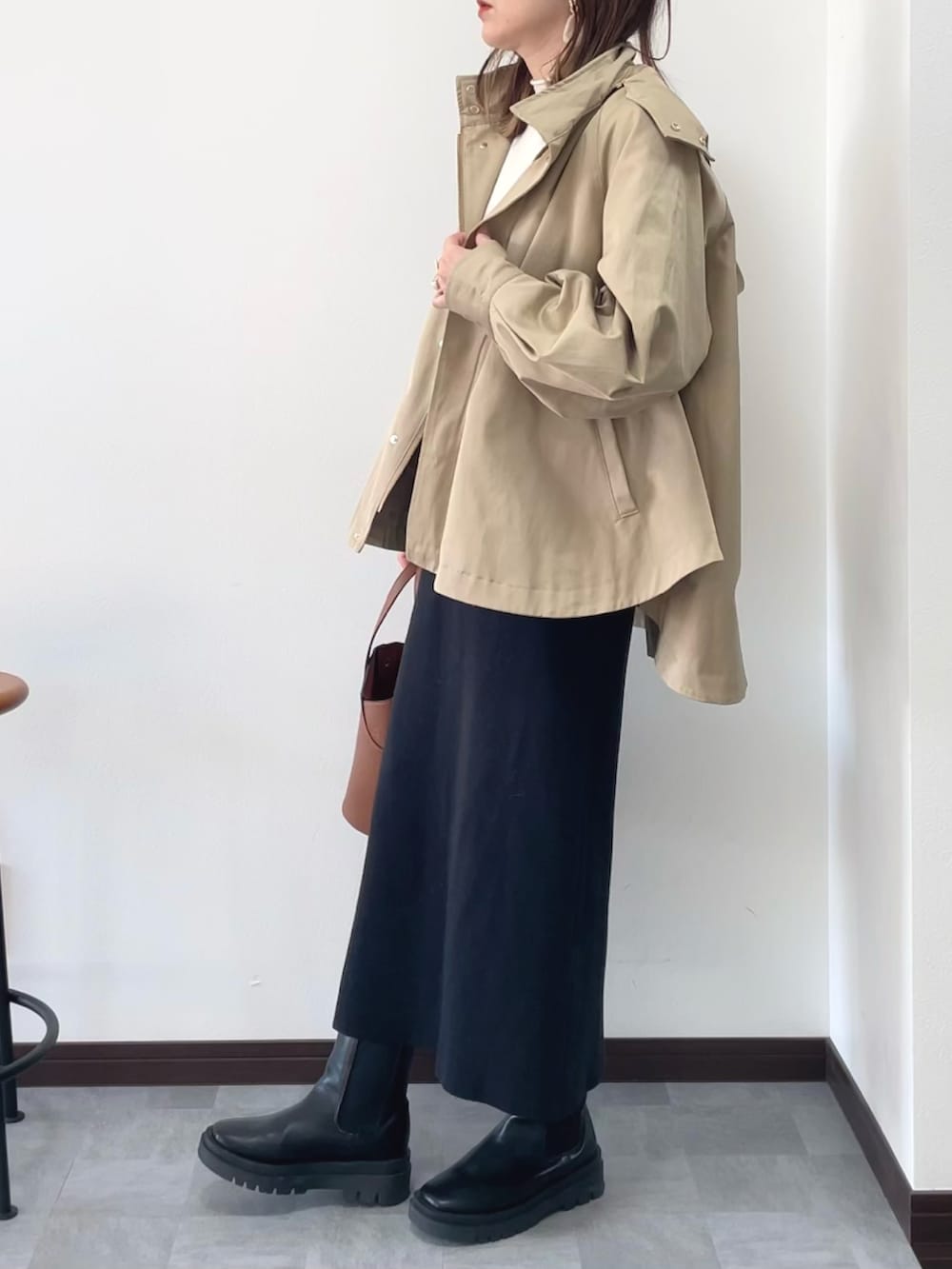 イエロー系のマウンテンパーカー、ブラック系のワンピース、ブラック系のブーツを着用したレディースの冬コーディネートの2枚目の写真