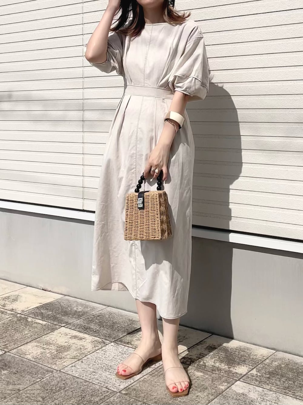 ベージュ系のワンピース、ブラウン系のかごバッグ、ベージュ系のサンダルを着用したレディースの夏コーディネートの2枚目の写真