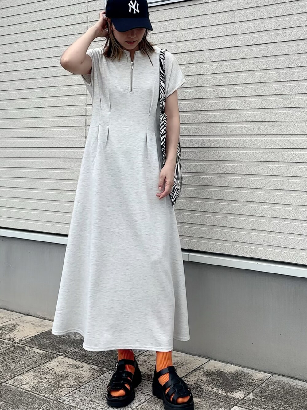 グレー系のワンピース、その他のショルダーバッグ、ブルー系のキャップを着用したレディースの夏コーディネートの2枚目の写真