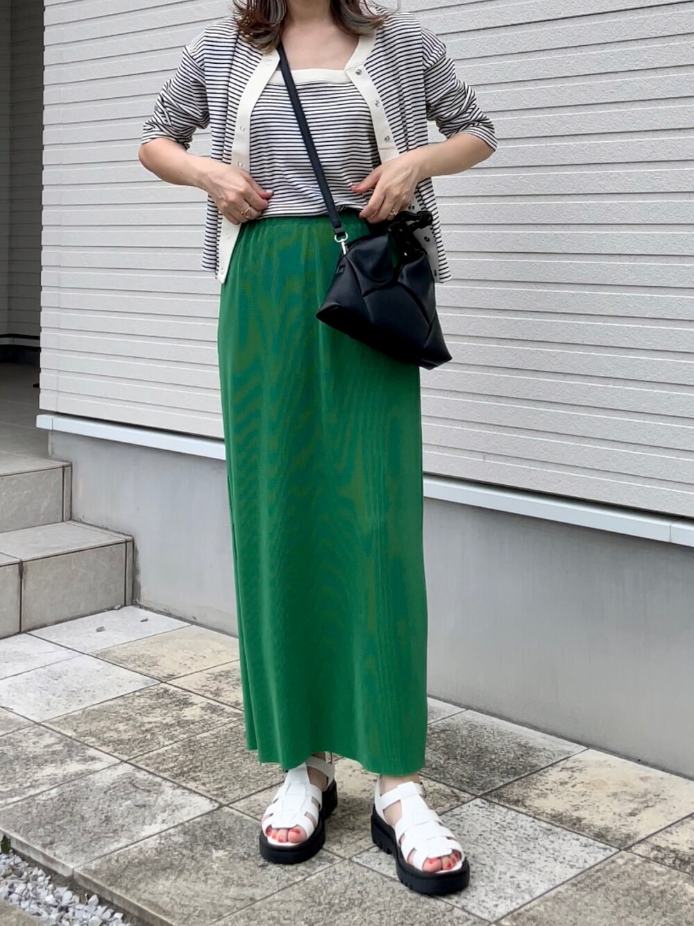 ホワイト系のアンサンブル、グリーン系のスカート、ホワイト系のサンダルを着用したレディースの夏コーディネートの2枚目の写真
