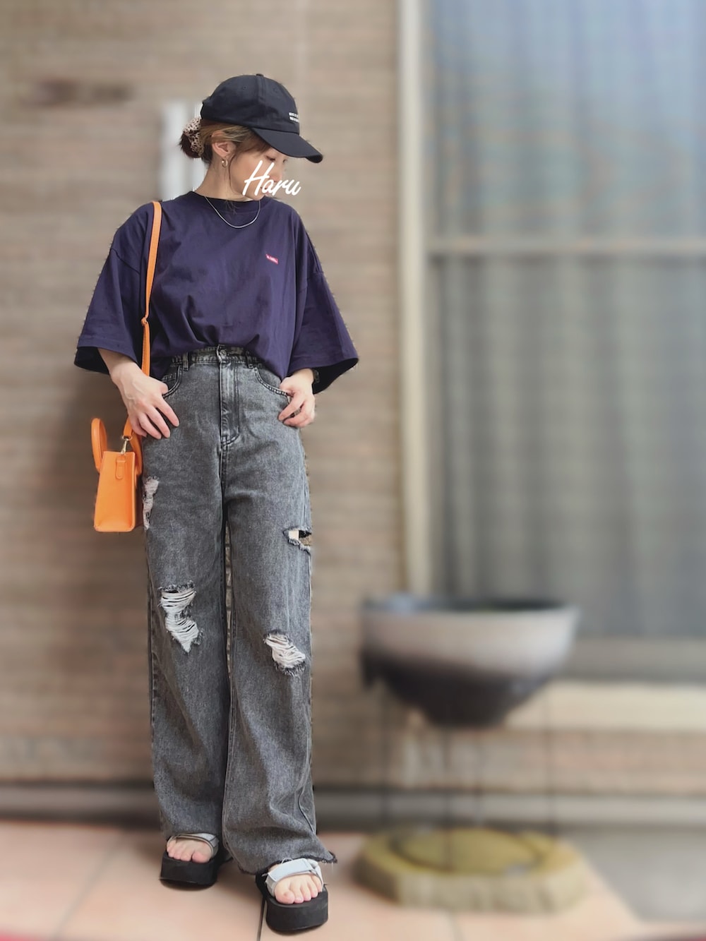 シルバー系のサンダル、グレー系のデニムパンツ、オレンジ系のショルダーバッグを着用したレディースの夏コーディネートの2枚目の写真