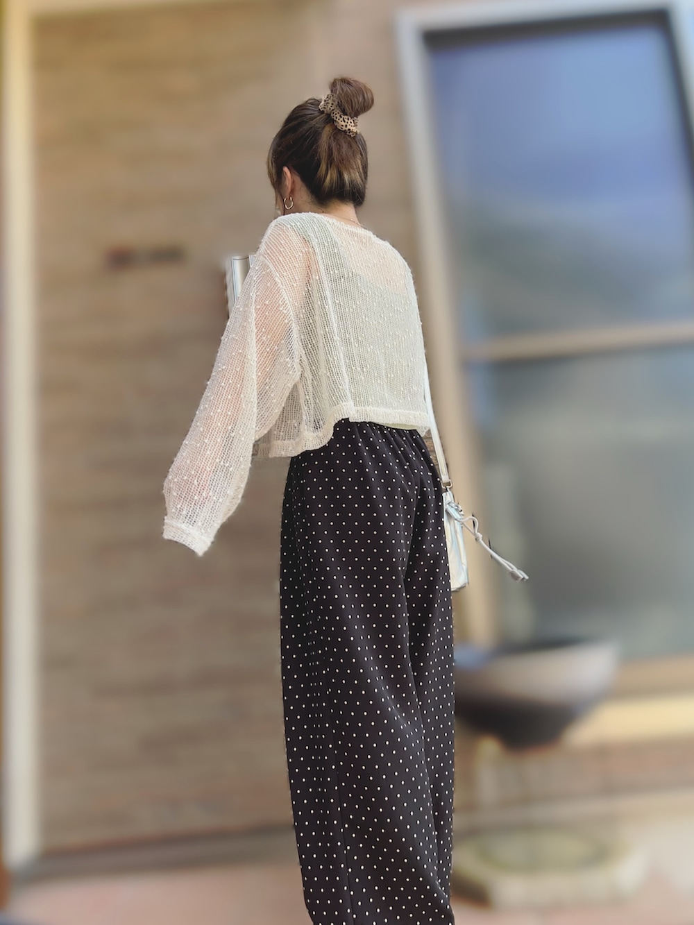 シルバー系のサンダル、シルバー系のショルダーバッグ、ブラック系のパンツを着用したレディースの夏コーディネートの2枚目の写真