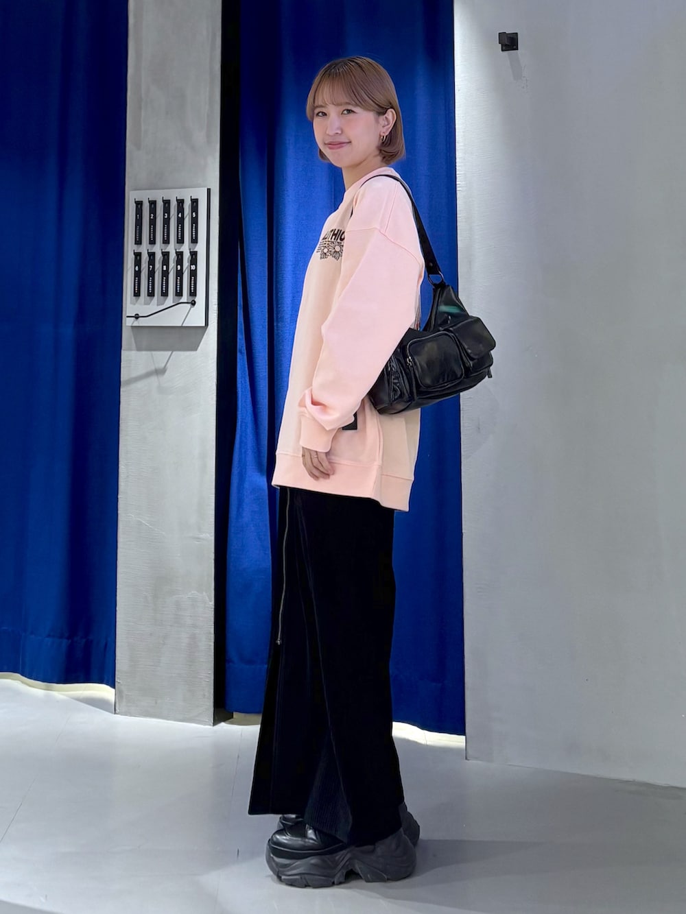 ピンク系のスウェット、グレー系のスカート、ブラック系のブーツを着用したレディースの冬コーディネートの2枚目の写真