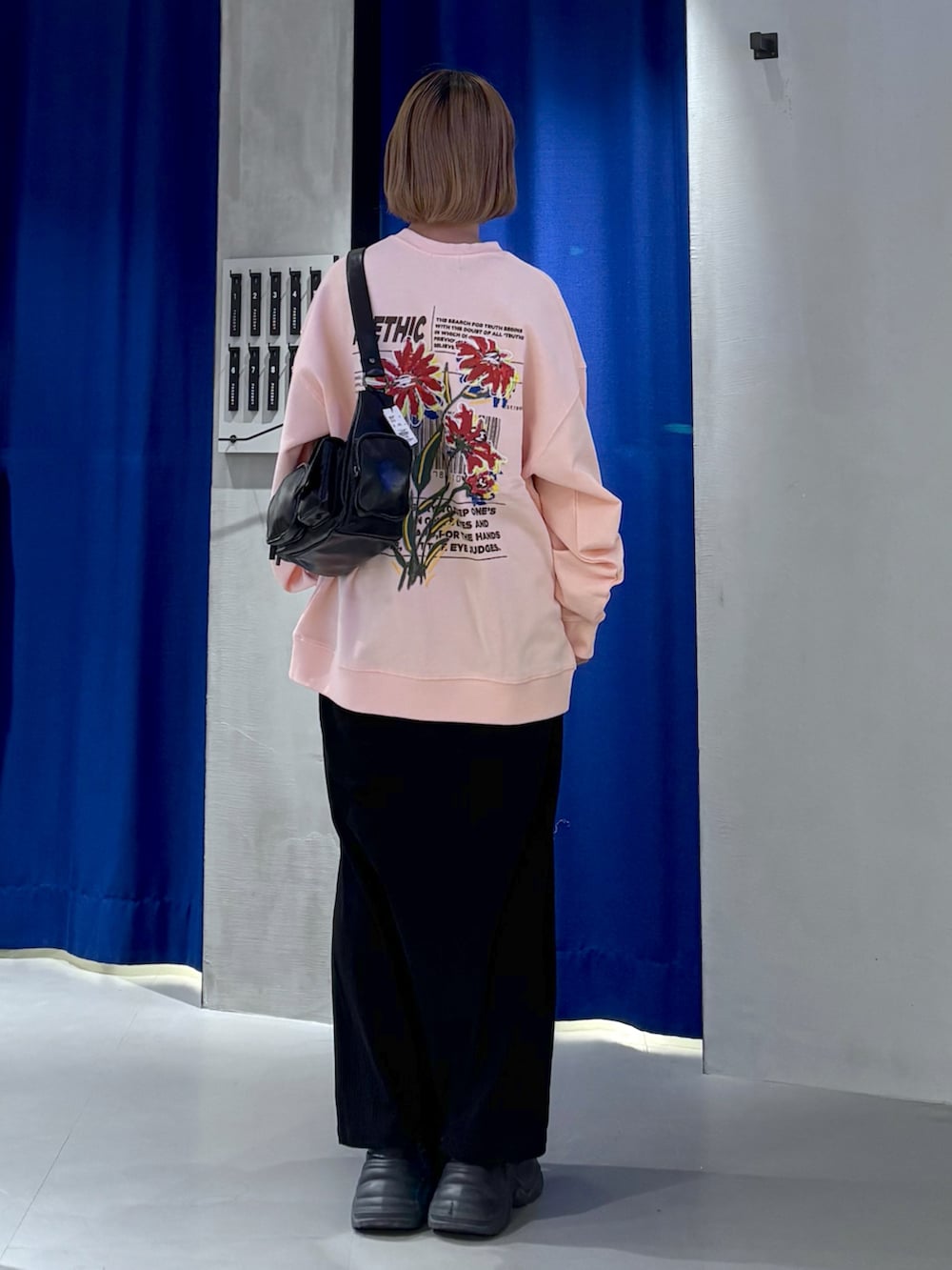 ピンク系のスウェット、グレー系のスカート、ブラック系のブーツを着用したレディースの冬コーディネートの3枚目の写真