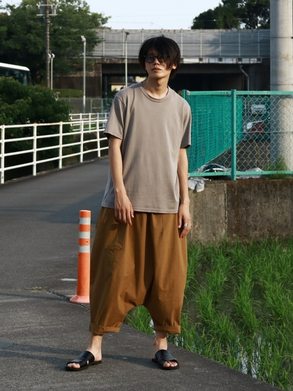 グレー系のTシャツ/カットソー、ベージュ系のパンツ、ブラック系のサンダルを着用したメンズの夏コーディネートの2枚目の写真