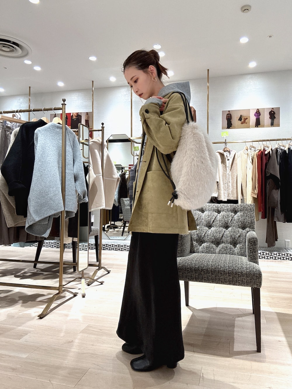 グレー系のパーカー、グリーン系のその他アウター、ブラック系のスカートを着用したレディースの秋コーディネートの3枚目の写真