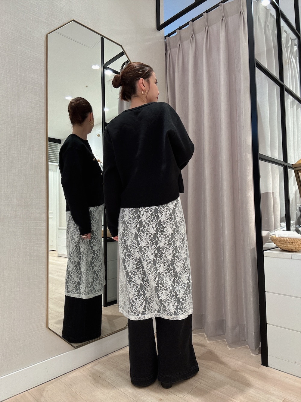 ブラック系のカーディガン/ボレロ、ホワイト系のスカート、グレー系のデニムパンツを着用したレディースの冬コーディネートの2枚目の写真