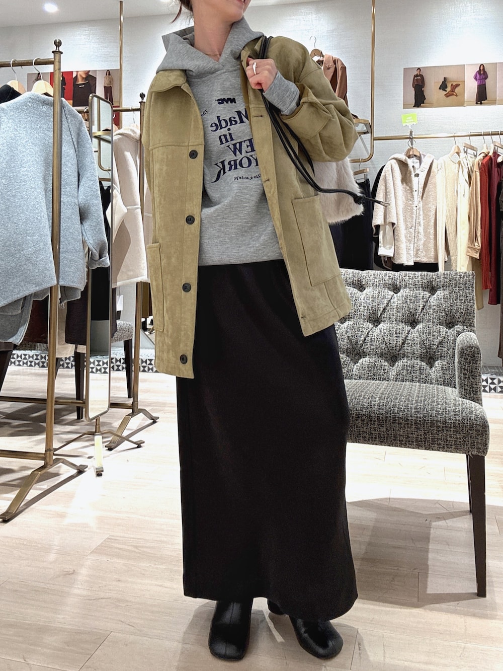 グレー系のパーカー、グリーン系のその他アウター、ブラック系のスカートを着用したレディースの秋コーディネートの2枚目の写真