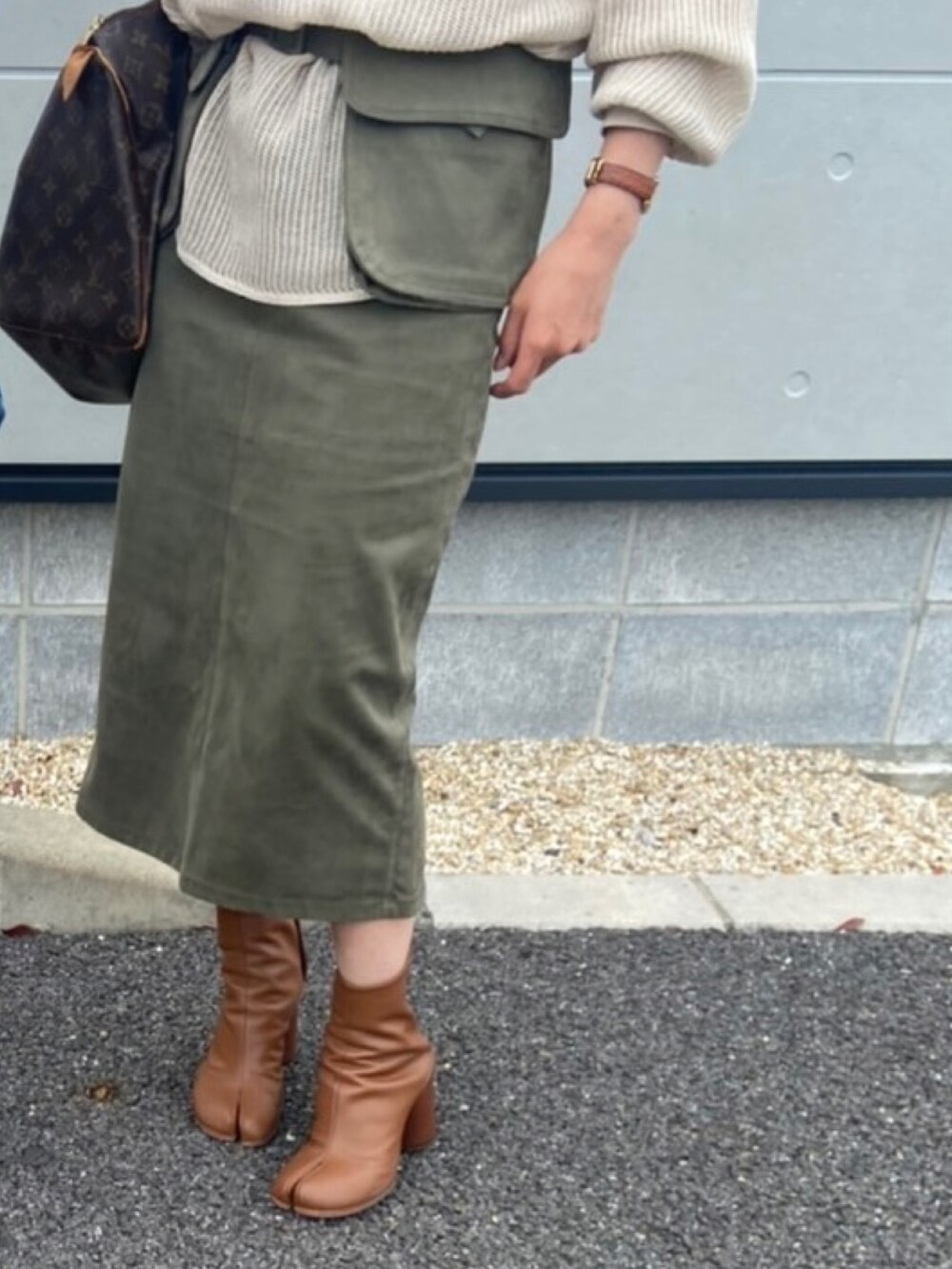 ベージュ系のトップス、グリーン系のスカート、ベージュ系のショルダーバッグを着用したレディースの秋コーディネートの3枚目の写真