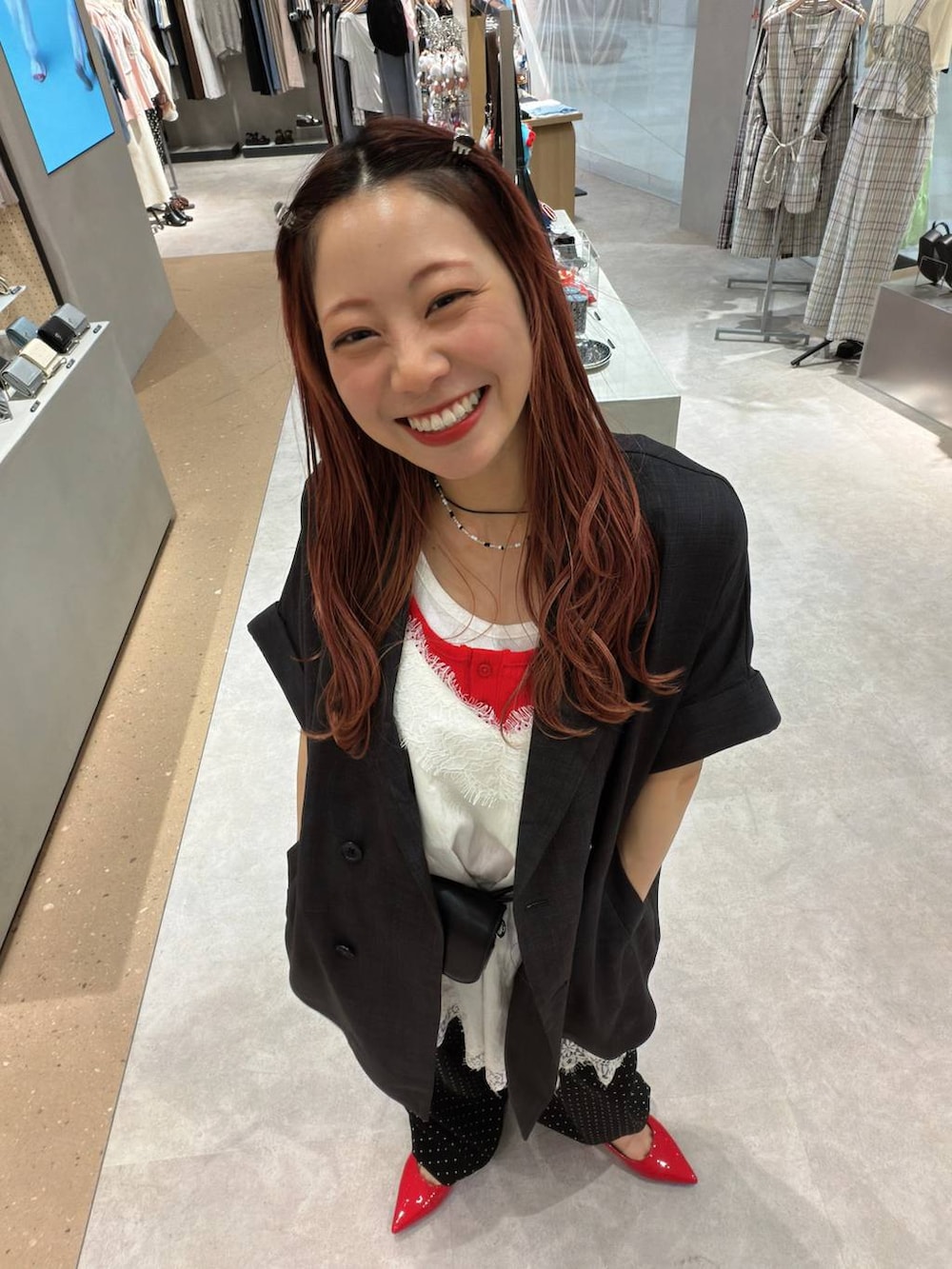 レッド系のパンプス、グレー系のテーラードジャケット、レッド系のタンクトップを着用したレディースの春コーディネートの6枚目の写真