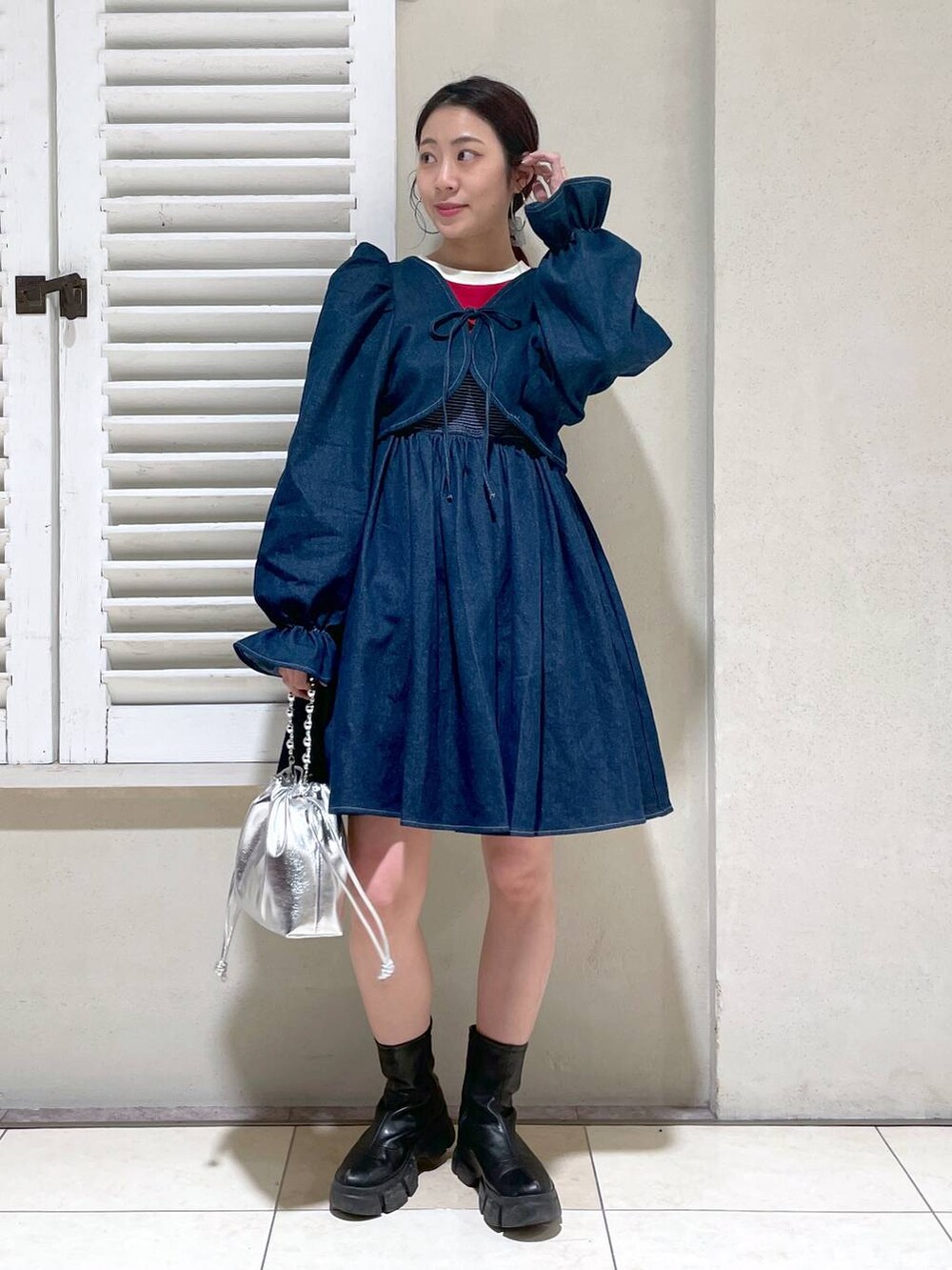 レッド系のTシャツ/カットソー、ブラック系のブーツ、ブラック系のショルダーバッグを着用したレディースの春コーディネートの2枚目の写真