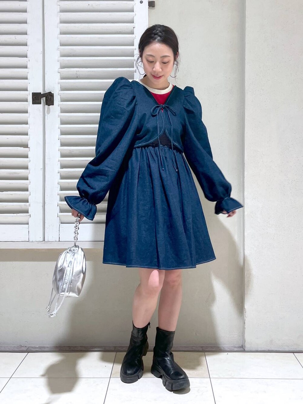 レッド系のTシャツ/カットソー、ブラック系のブーツ、ブラック系のショルダーバッグを着用したレディースの春コーディネートの3枚目の写真