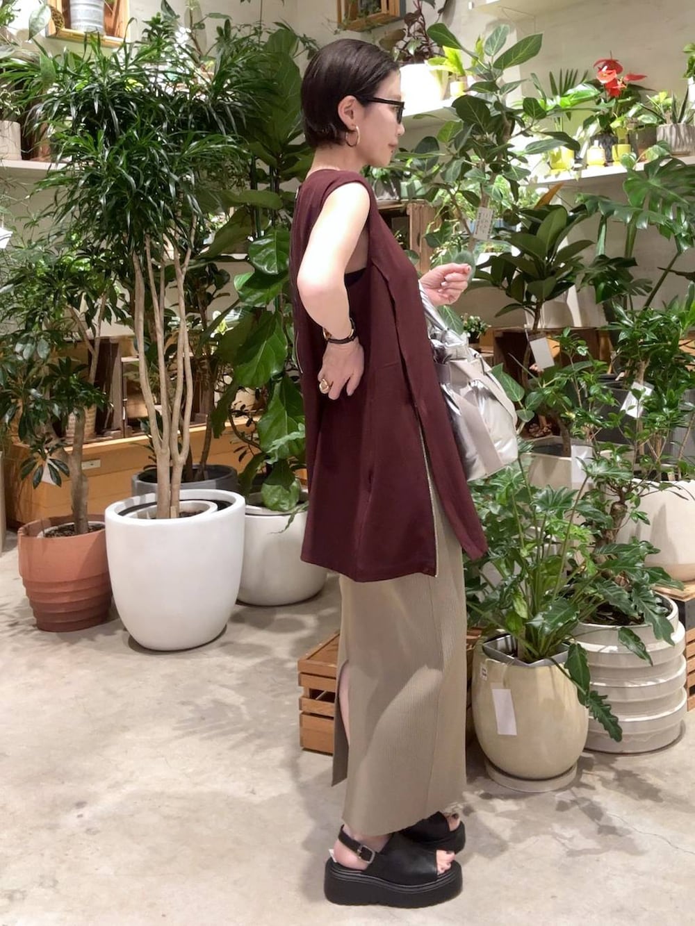 グリーン系のスカート、シルバー系のトートバッグ、ブラック系のサンダルを着用したレディースの夏コーディネートの2枚目の写真