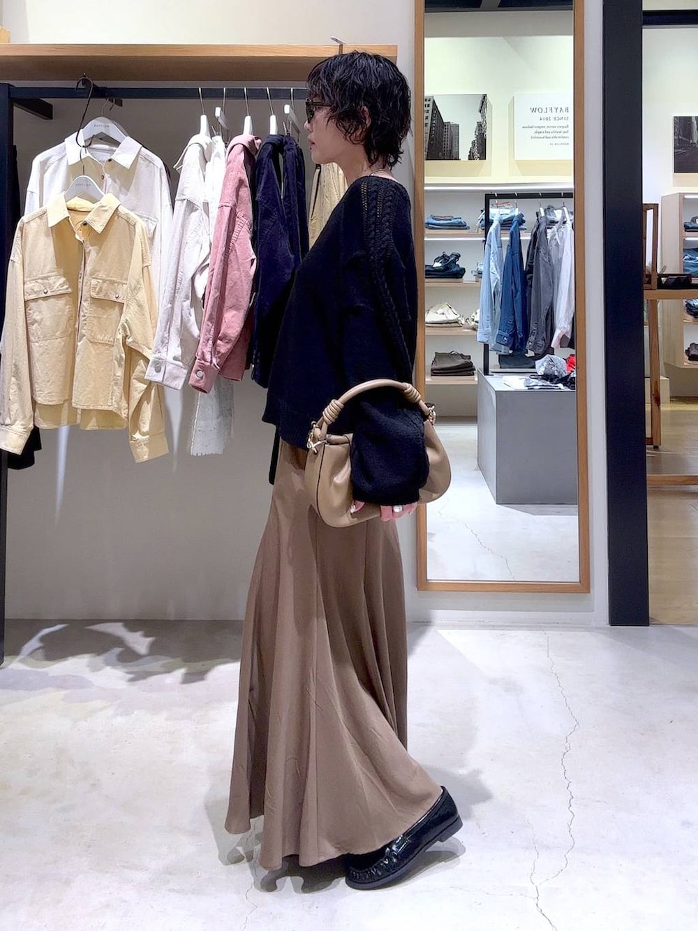 ベージュ系のハンドバッグ、ブラック系のローファー、ブラック系のニット/セーターを着用したレディースの冬コーディネートの2枚目の写真