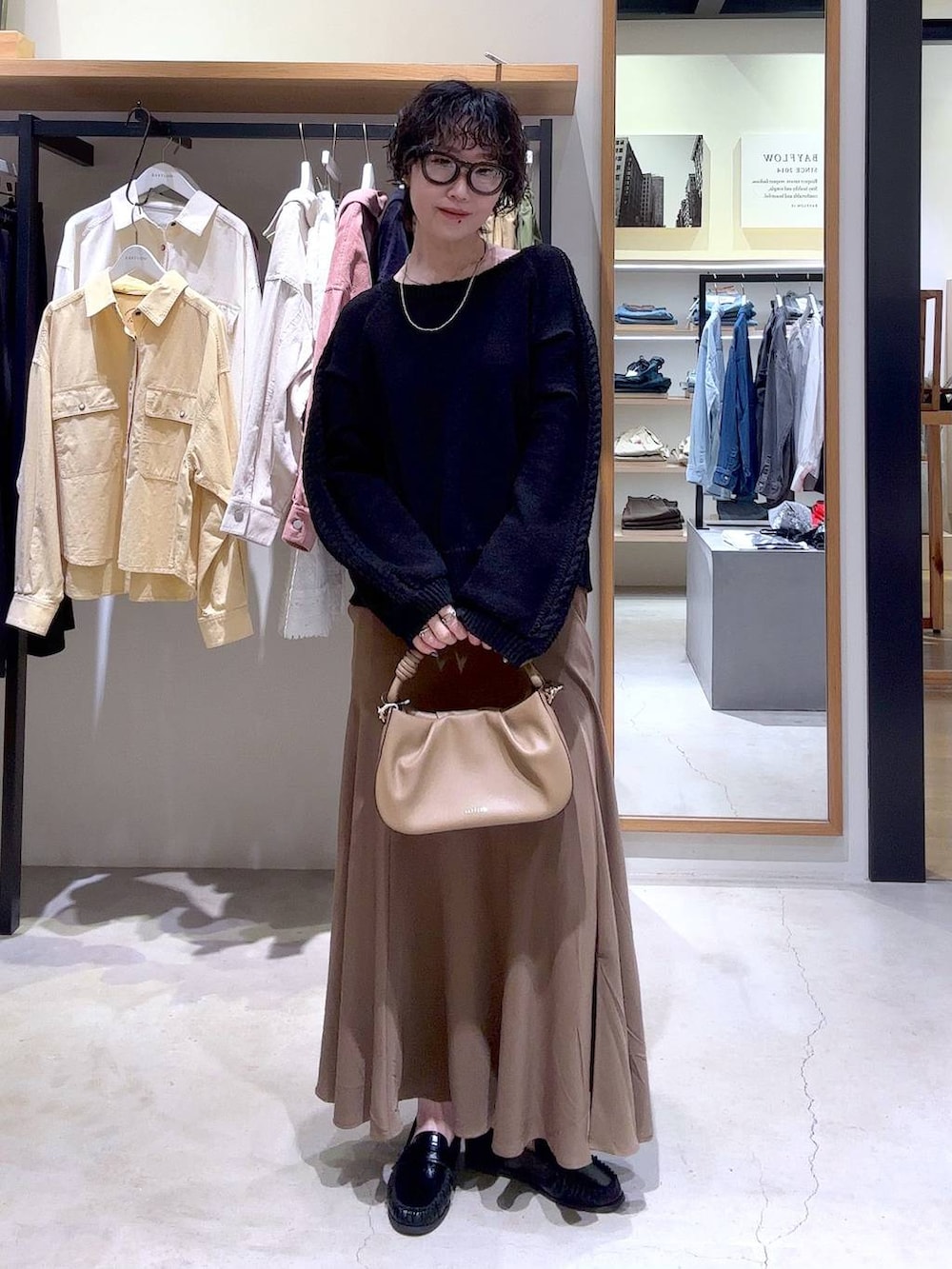 ベージュ系のハンドバッグ、ブラック系のローファー、ブラック系のニット/セーターを着用したレディースの冬コーディネートの4枚目の写真