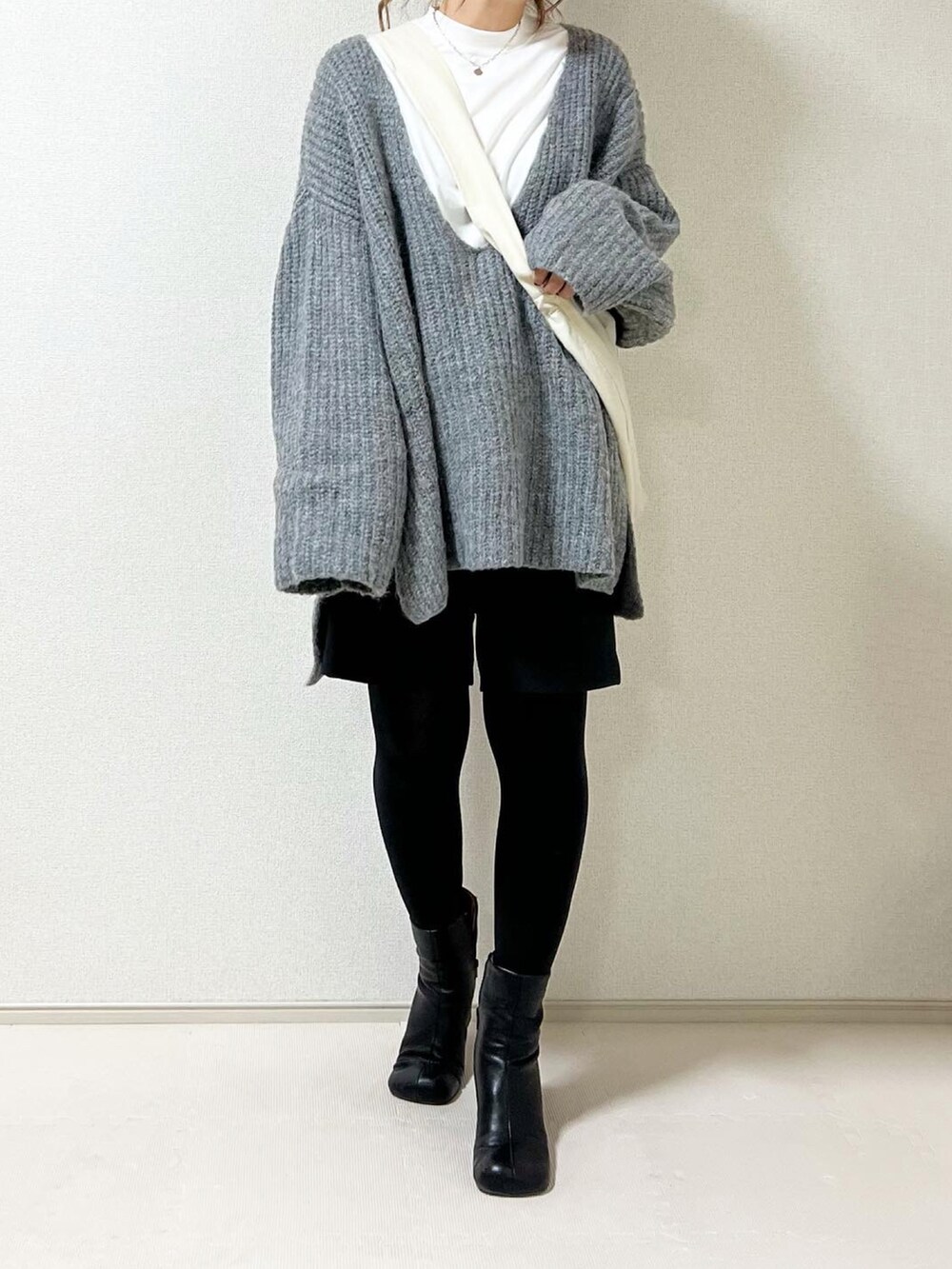 ホワイト系のショルダーバッグ、ブラック系のブーツを着用したレディースの秋コーディネートの3枚目の写真